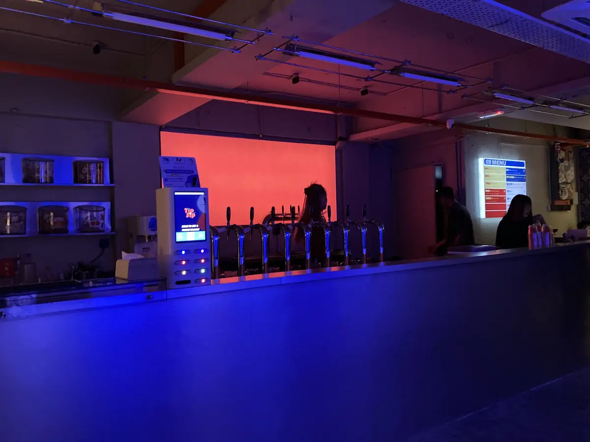 The bar under blue light with a row of cocktail taps