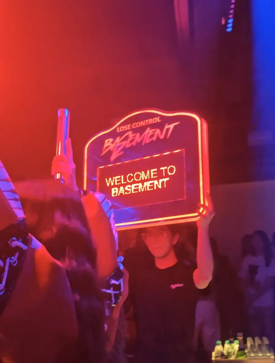 Welcome to Basement neon board held up in the club